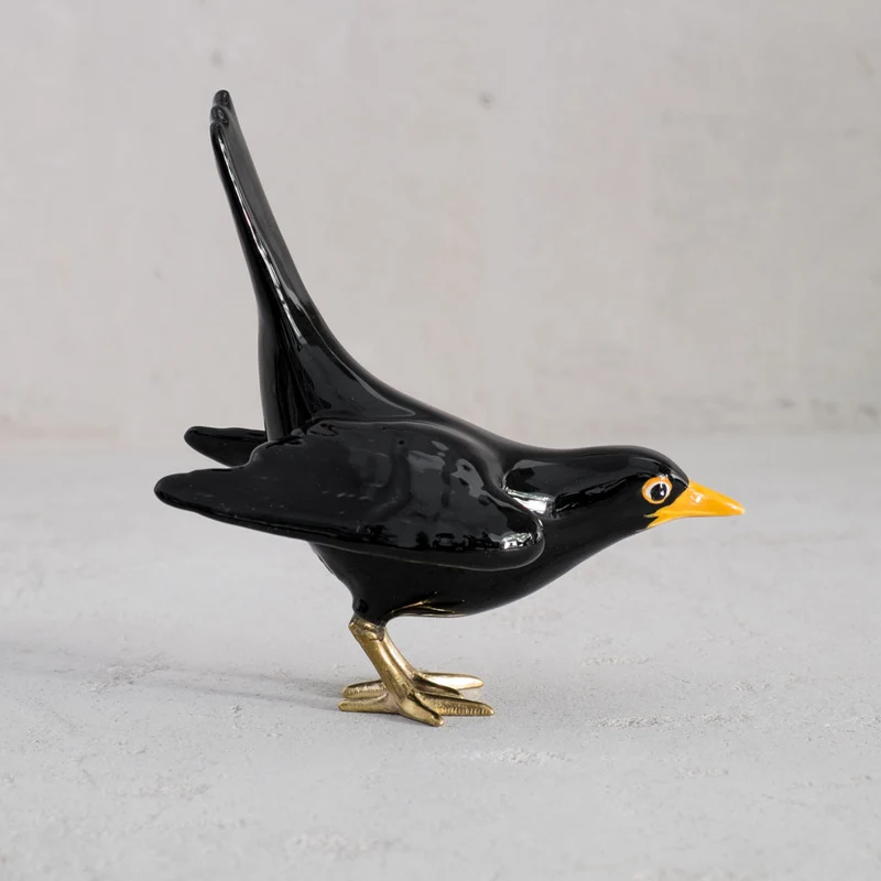 Amsel mit Messingbeinen und offenen Flügeln