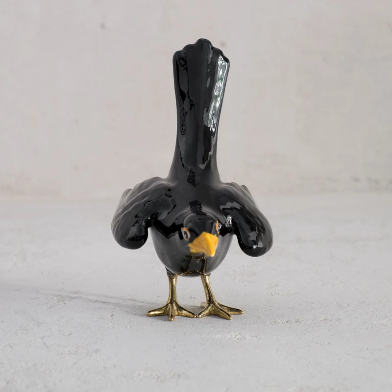 Amsel mit Messingbeinen und offenen Flügeln